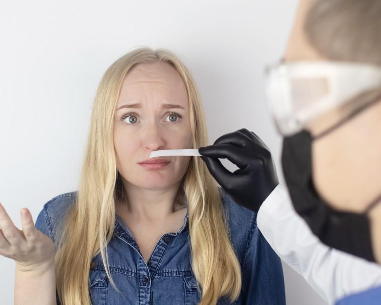 photo of worried woman sniffing a scent strip of paper