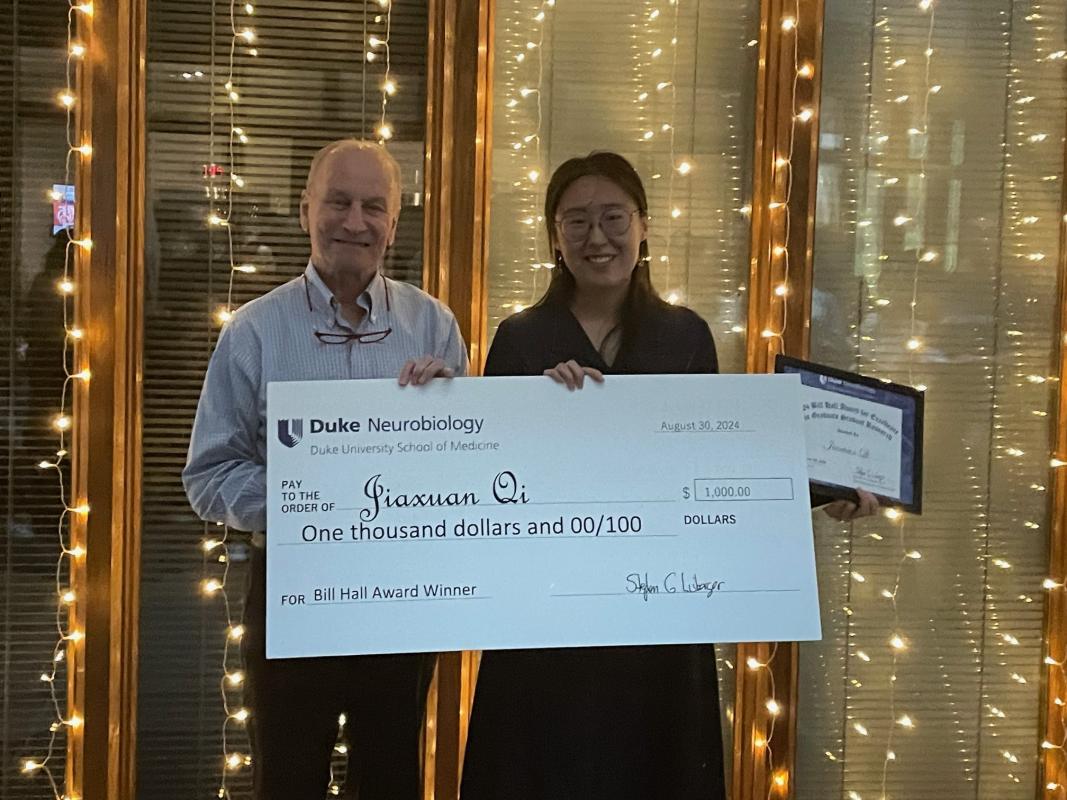 Jiaxuan Qi and Steve Lisberger, holding giant check for $100 for Bill Hall Award