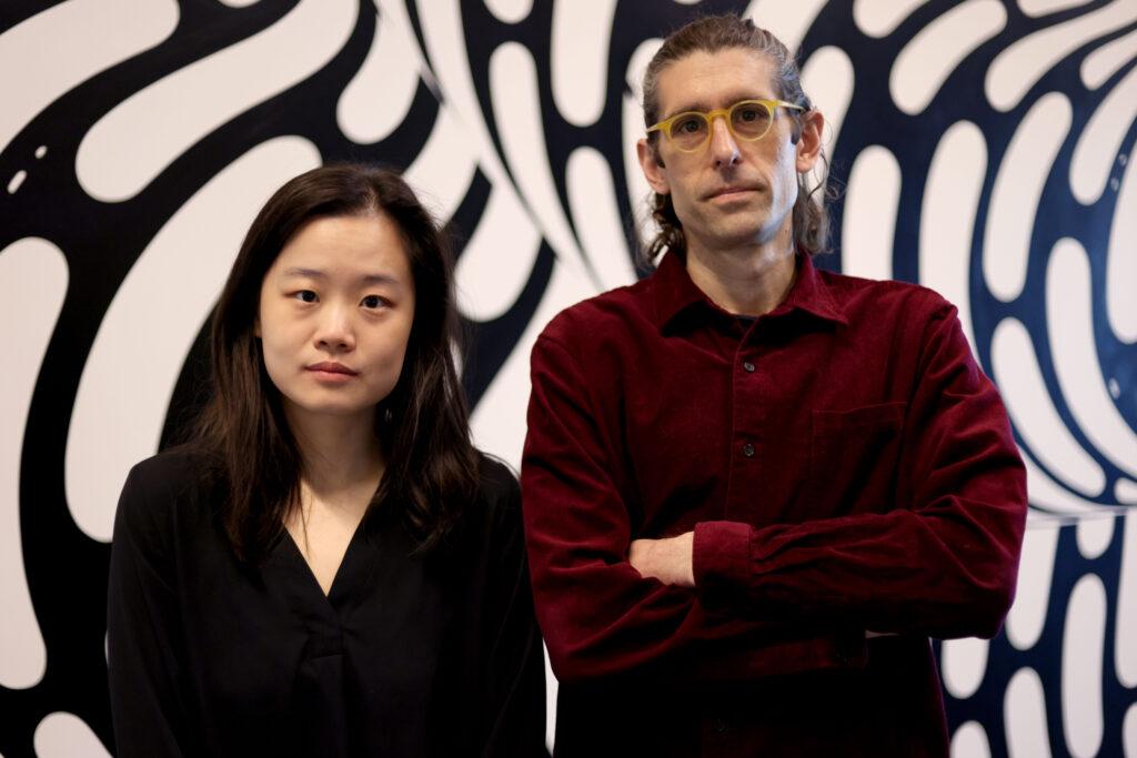 Tim Dunn and a collaborator standing in front of geometric background
