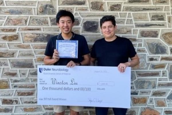 Winston Liu and Diego Bohorquez stand with giant check for $1000